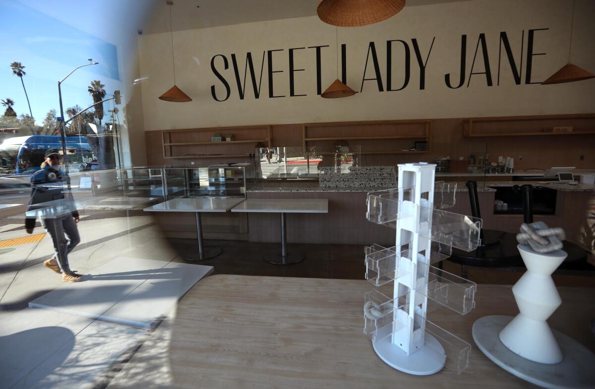 A pedestrian, reflected in the display window at Sweet Lady Jane, walks past the shuttered bakery in Santa Monica