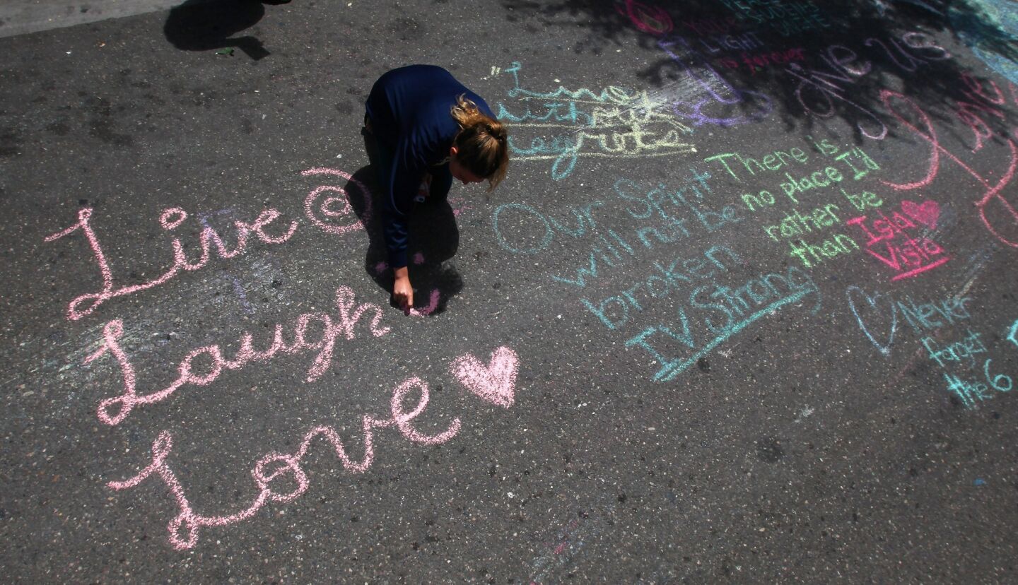 UC Santa Barbara student Shoshana Cohen, 20, writes a chalk message in the street in front of the I.V. Deli Mart in Isla Vista, where one of last week's rampage victims was gunned down.