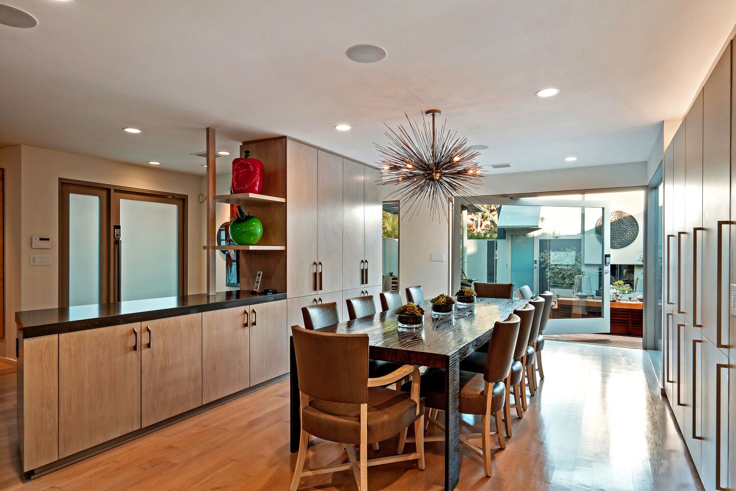 A dining area with a long table and chairs and cabinetry.