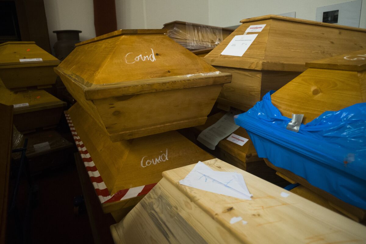 Caskets labelled with the word 'Covid' are stacked with others coffins in the memorial hall of the crematorium in Meissen, Germany, Monday, Jan. 11, 2021. The crematorium would typically have 70 to 100 caskets on site at this time of year, now it has 300 bodies waiting to be cremated and more are brought to the crematorium every day. (AP Photo/Markus Schreiber)