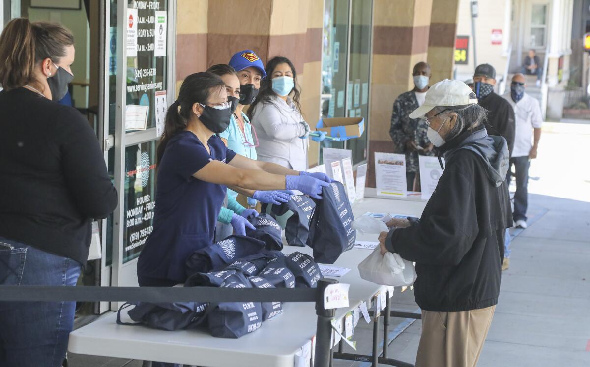 Seniors line up at the Gary & Mary West Senior Wellness Center in downtown to receive dental hygiene kits from the Senior Dental Center on May 22, 2020 in San Diego, California.