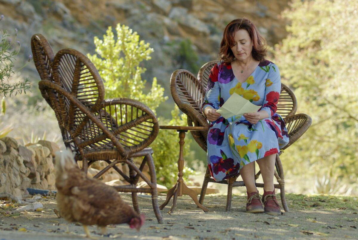 A woman in a pattern dress sitting outside reading a note