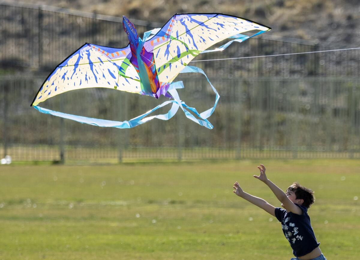 Hector Avila, 6, reaches for a kite 