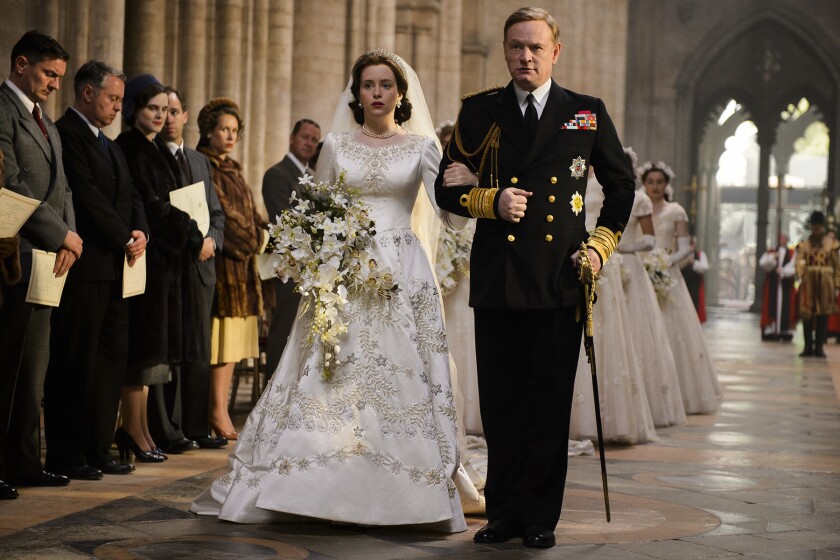 A man in royal clothing walks a bride down an aisle
