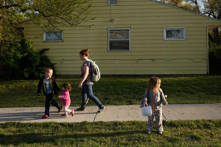 3077961_la-na-Health-Care-Series-Kansas.Topeka, Kan. resident Clarisa Corber walks her children Lee, 6, Kaley, 1, and Abigail, 3, right, along side their home to the car as they leave their house for school and daycare on Thursday, April 25, 2019 in Topeka, Kan. Clarisa and her husband Zack Corber, who both work while having three kids, estimate that they have over $12 thousand in unpaid medical bills that have gone to collection agencies.
