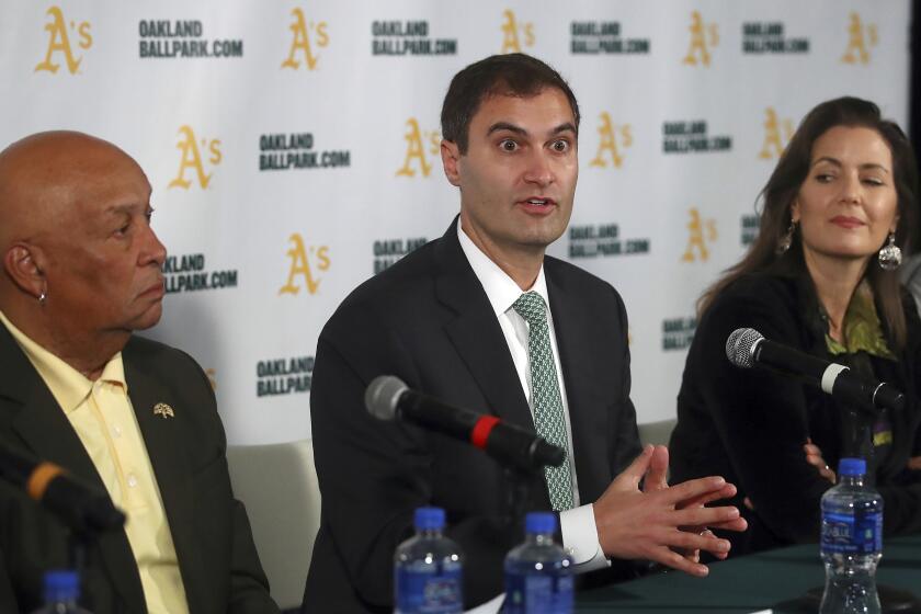 FILE - Oakland Athletics President Dave Kaval, center, speaks beside Oakland Mayor Libby Schaaf, right, and Ces Butner, President of the Board of Port Commissioners, during a baseball news conference in Oakland, Calif., in this Wednesday, Nov. 28, 2018, file photo. Major League Baseball instructed the Athletics to explore relocation options as the team tries to secure a new ballpark it hopes will keep the club in Oakland in the long term. MLB released a statement Tuesday, May 11, 2021, expressing its longtime concern that the current Coliseum site is “not a viable option for the future vision of baseball.” (AP Photo/Ben Margot, FIle)