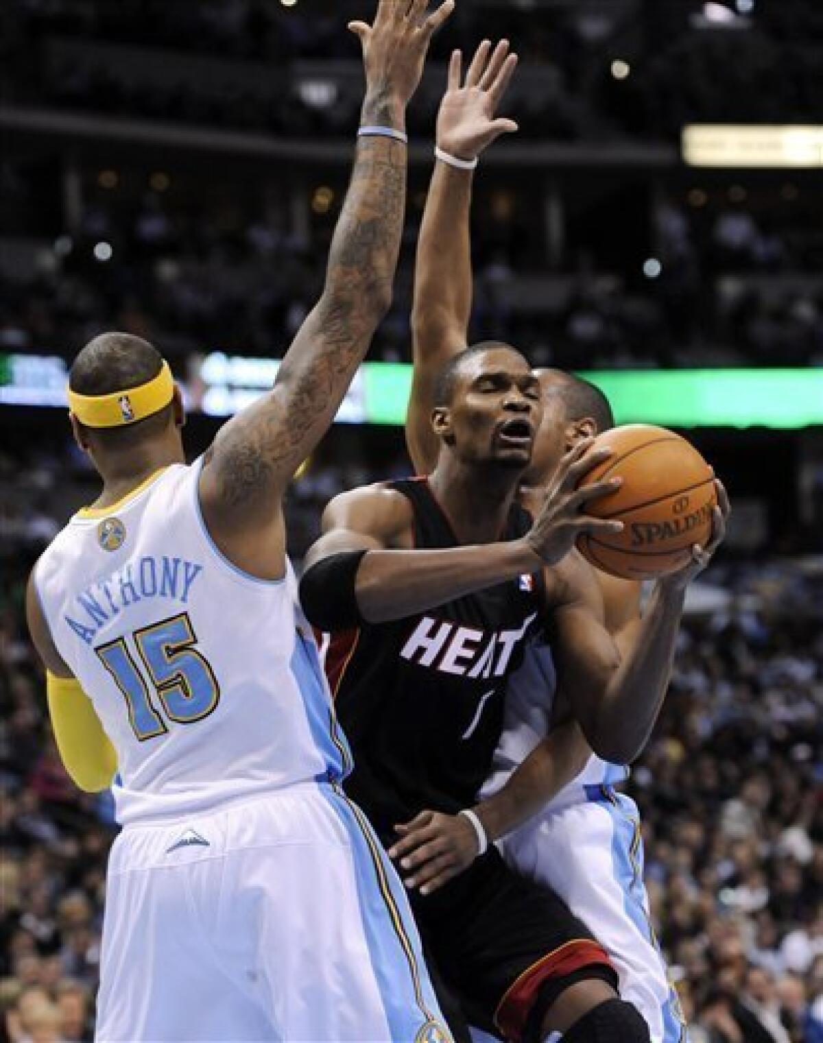 Carmelo Anthony of the Denver Nuggets dunks over Dwyane Wade of