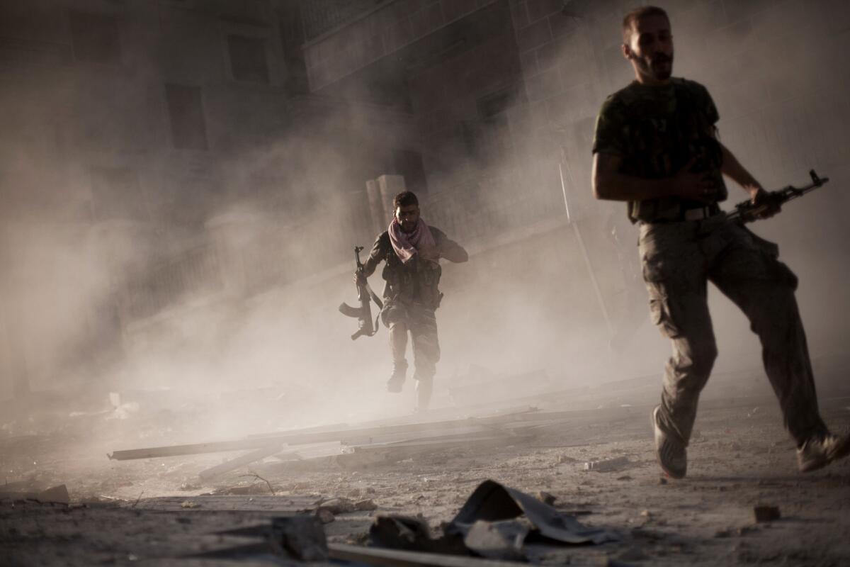 Free Syrian Army fighters run after attacking a Syrian Army tank during fighting in Aleppo, Syria.