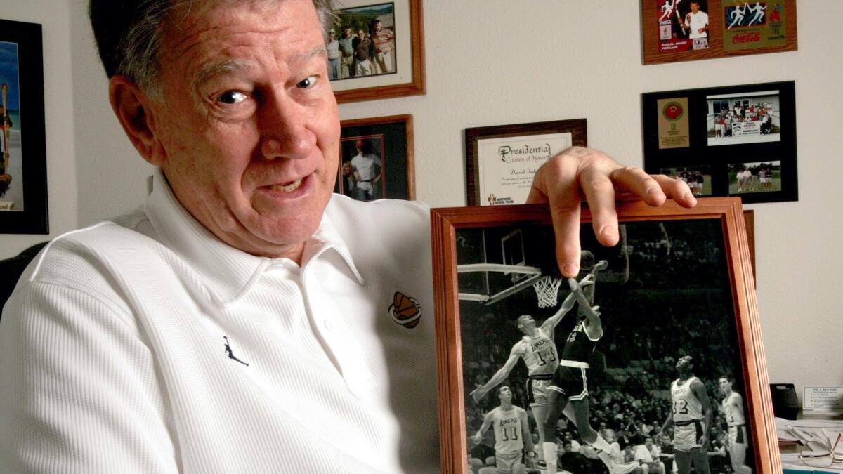 Darrall Imhoff at his office in Springfield, Ore., on March 3, 2005, with a photo of him trying to block a shot by 76ers center Wilt Chamberlain.