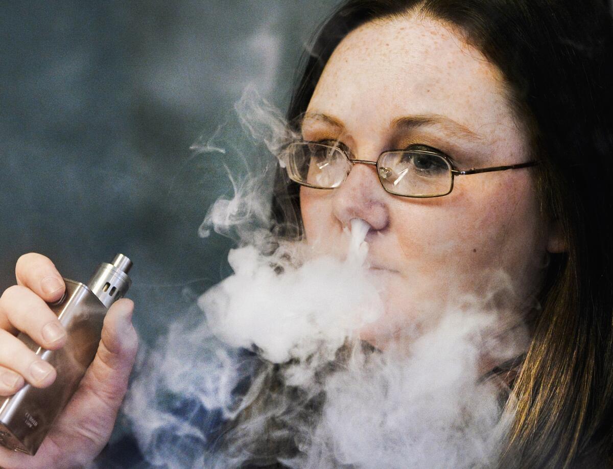An employee at a retail shop that specializes in electronic cigarettes exhales vapor at the store in East Peoria, Ill. on Feb. 17.