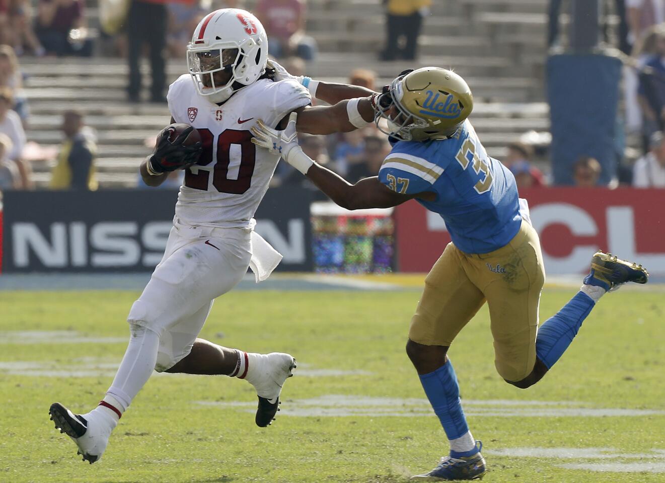 Stanford running back Bryce Love puts a stiff arm to the face of Bruins free saftey Quentin Lake on a short gain in the second quarter.