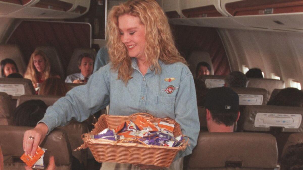 A Southwest Airlines flight attendant hands out snacks on a 1996 flight from Oakland to Burbank. Although peanuts "forever will be part of Southwest’s history and DNA," the airline said, it plans to stop offering them to passengers on Aug. 1.
