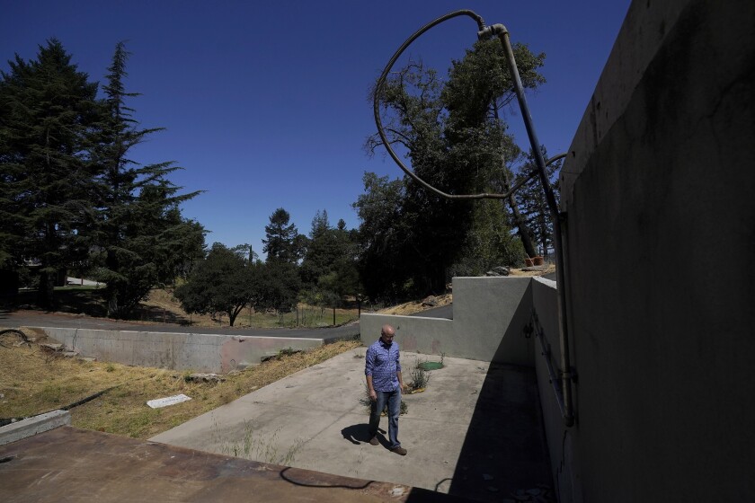 Will Abrams walks on the lot of his family home that was destroyed by wildfires in 2017 while interviewed in Santa Rosa, Calif., Thursday, June 24, 2021. Pacific Gas & Electric's CEO is pledging that the future will get “easier” and “brighter.” But those words are ringing hollow one year after PG&E emerged from a complex bankruptcy triggered by a succession of harrowing wildfires ignited by its long-neglected electrical grid. (AP Photo/Jeff Chiu)