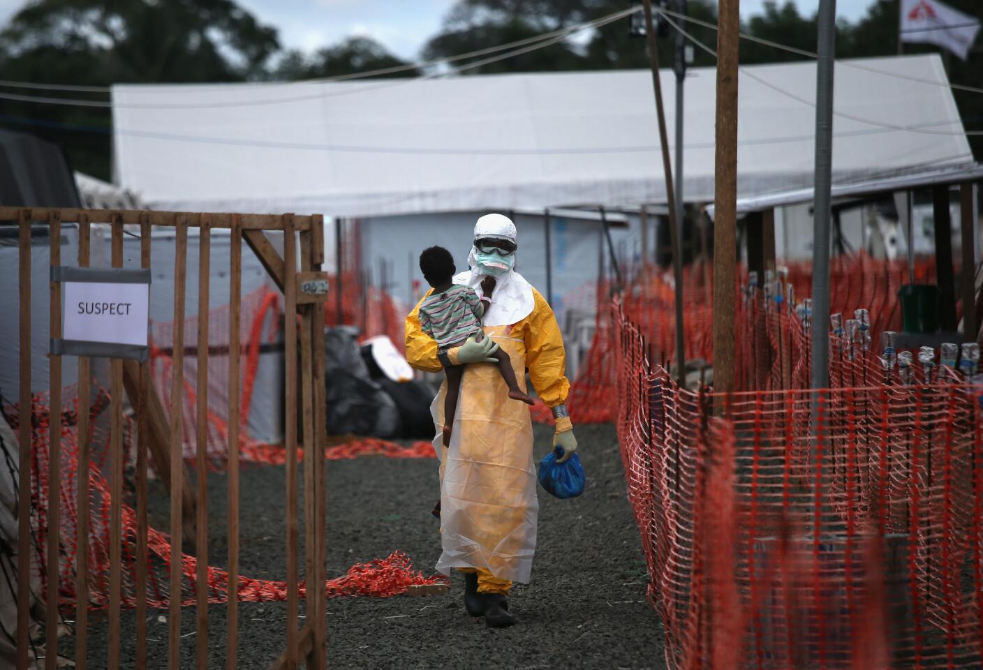 A Doctors Without Borders health worker in protective clothing carries a child suspected of having Ebola at a treatment center in Paynesville, Liberia. The girl and her mother, showing symptoms of the deadly disease, were awaiting test results on Oct. 5.