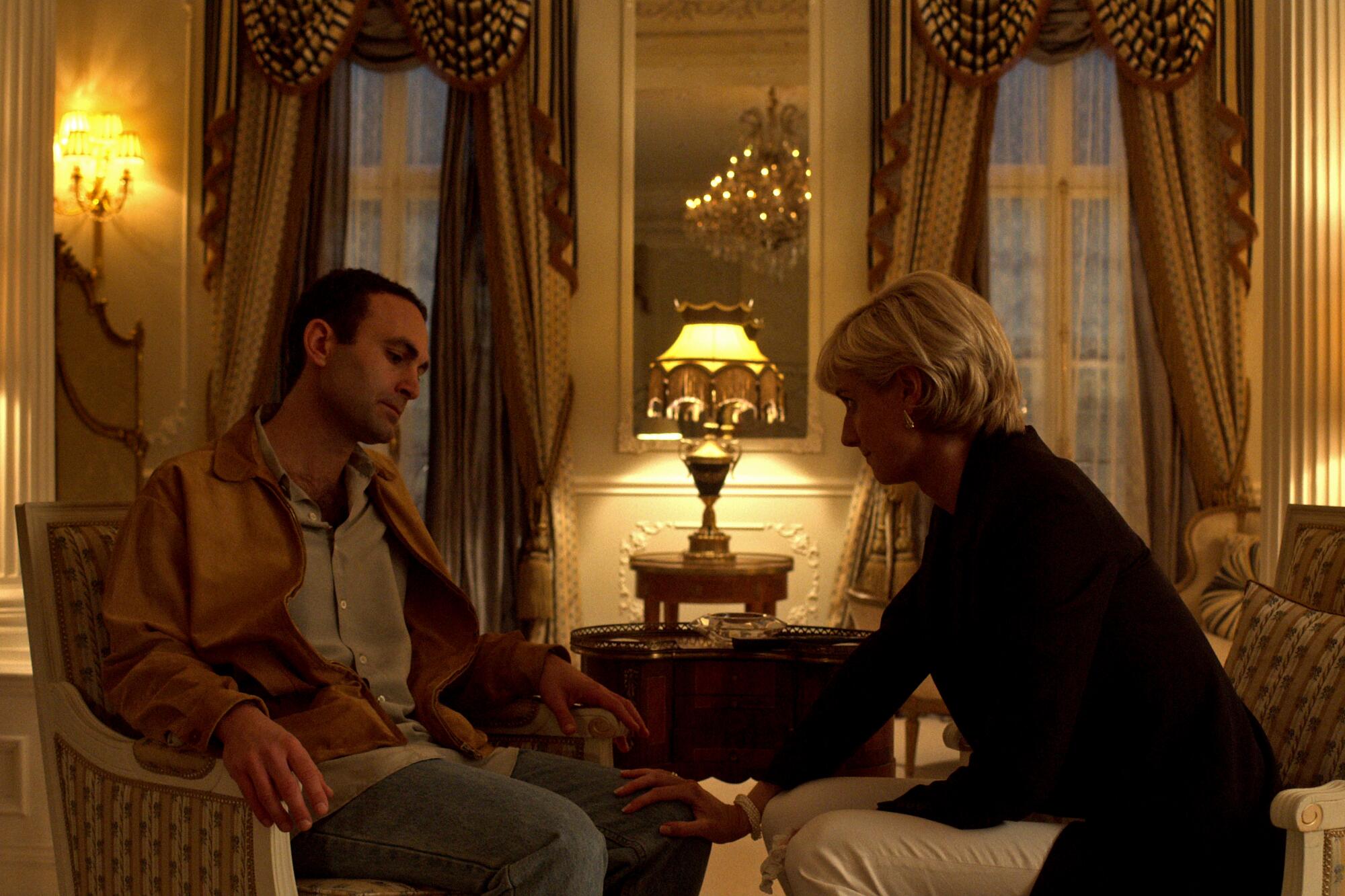 Khalid Abdalla as Dodi, left, and Elizabeth Debicki as Princess Diana, sit in chairs across from each other in a lit room.