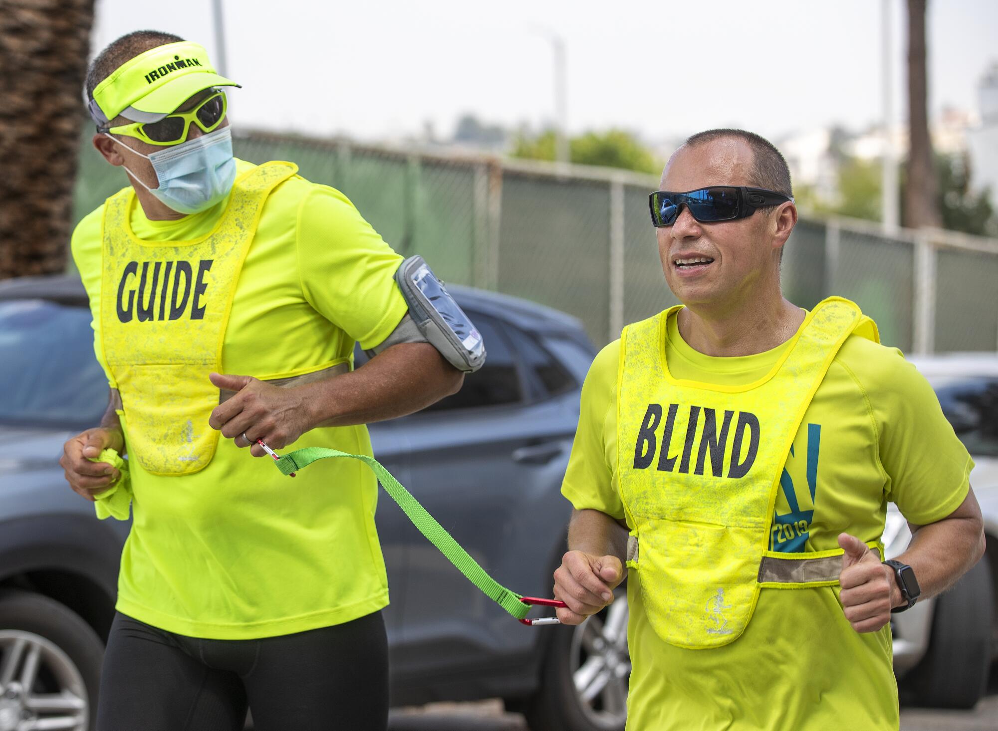 Tony Duenas, 53, right, a marathon runner who is blind, and his guide Ray Alcanter, demonstrate the technique they use