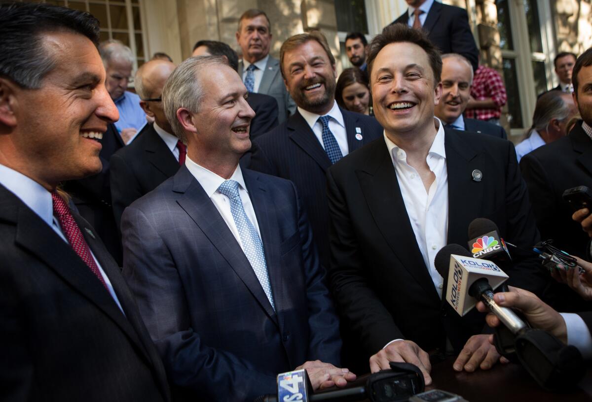 Tesla CEO Elon Musk, right, speaks to the media after a news conference announcing a tax package for the electric automaker.