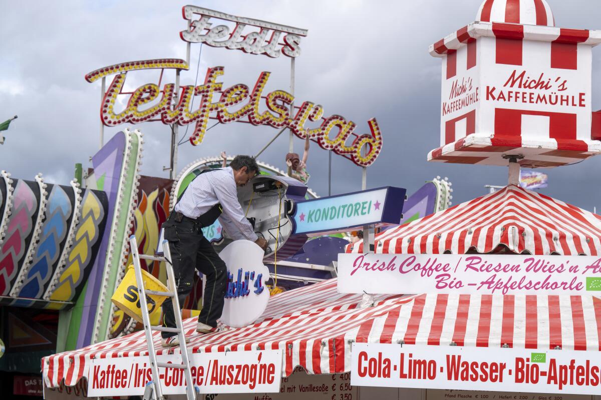 A man mounts a light advertisement on a booth on the Oktoberfest grounds in Munich, Germany, Thursday, Sept. 15, 2022. The Oktoberfest is on tap again in Germany after a two-year pandemic interruption. The beer will be just as cold and the pork knuckle just as juicy. But brewers and visitors are under pressure from inflation in ways they could hardly imagine in 2019. (Peter Kneffel/dpa via AP)