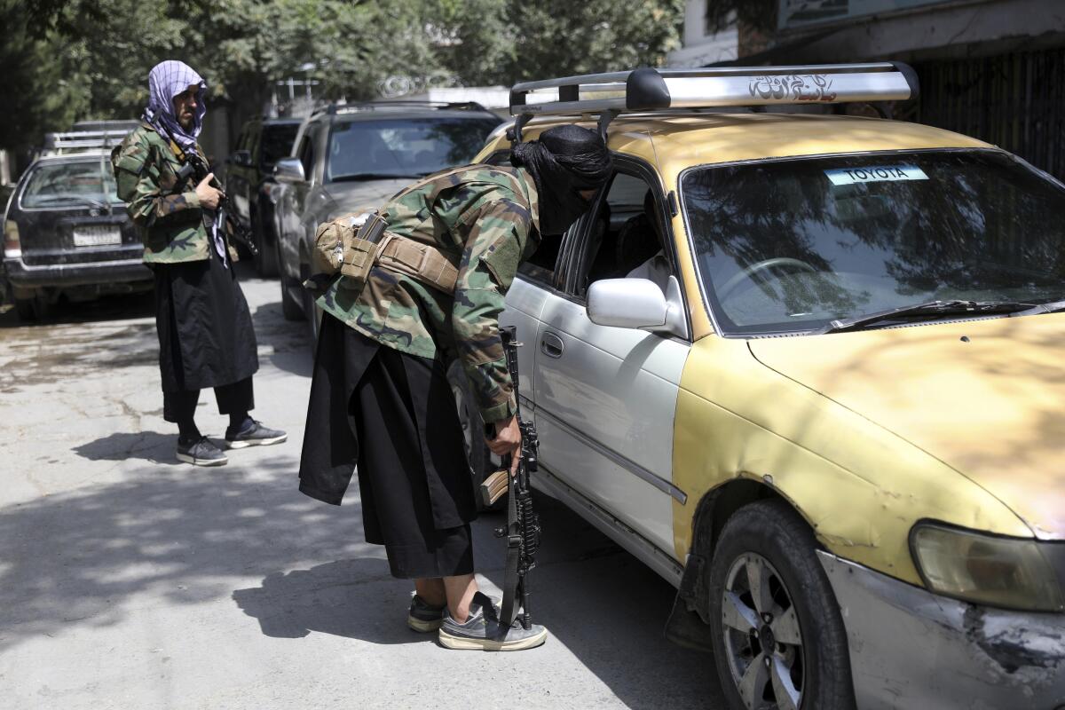 Taliban fighters search a vehicle at a checkpoint on the road in the Wazir Akbar Khan neighborhood in Kabul, Afghanistan