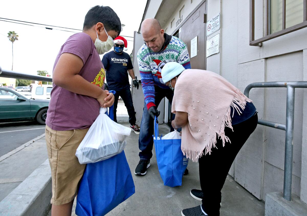 Huntington Beach Mayor Pro Tem Tito Ortiz hands a bagged turkey to Amada Cardozo.