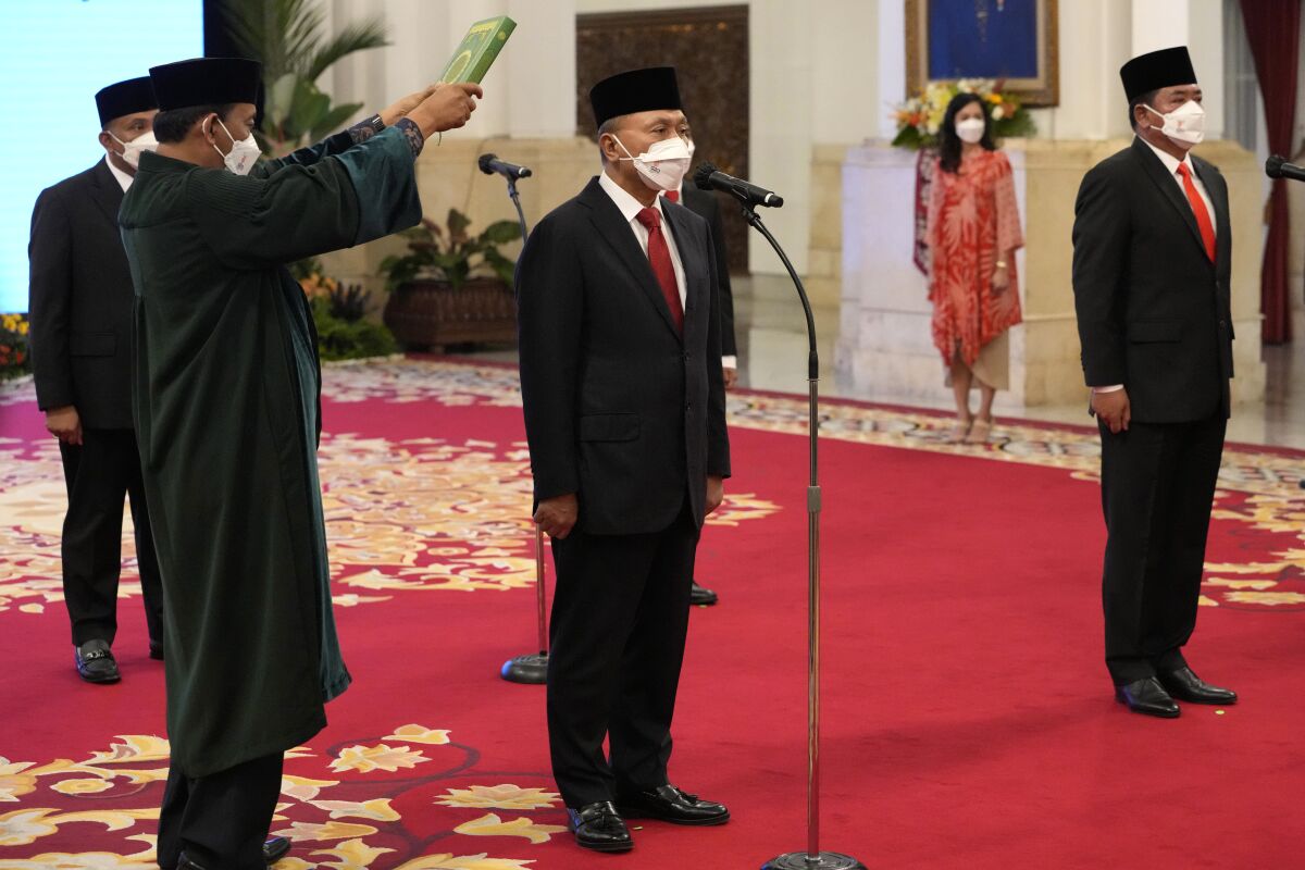 A Muslim cleric, left, holds a Quran over Indonesian Trade Minister Zulkifli Hasan center, and Indonesian Agrarian and Spatial Planning Minister Hadi Tjahjanto, right, during an inauguration ceremony at Merdeka Palace in Jakarta, Indonesia, Wednesday, June 15, 2022. Indonesia's President Joko Widodo announced a Cabinet reshuffle Wednesday, replacing key economic ministers with the aim to revive sputtering growth and stabilize national cooking oil shortage and price hike. (AP Photo/Achmad Ibrahim)
