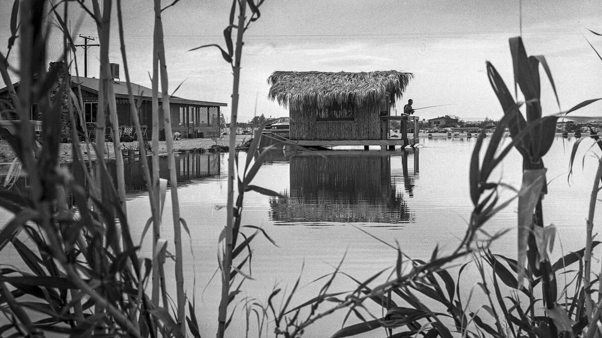 March 27, 1965: Eugene Cowell fishes from a tiki house in his one-acre lake, one of the 35 that blossomed in the desert community of Newberry. He says catfish eat from his wife's hand.  