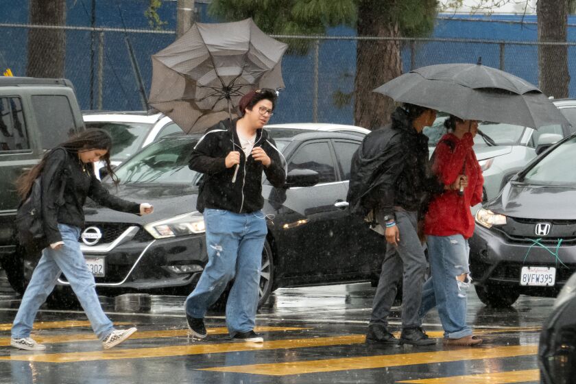 LOS ANGELES, CA - MARCH 21: Wind catches an umbrella as students in Van Nuys leave school during a rainy afternoon on Tuesday, March 21, 2023. (Myung J. Chun / Los Angeles Times)