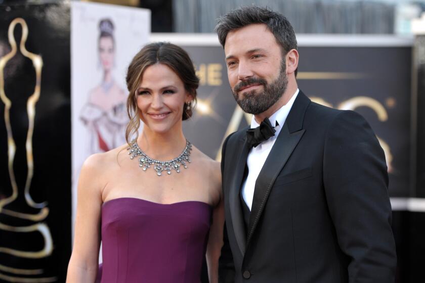 A woman in a purple dress posing with a man in a black tuxedo