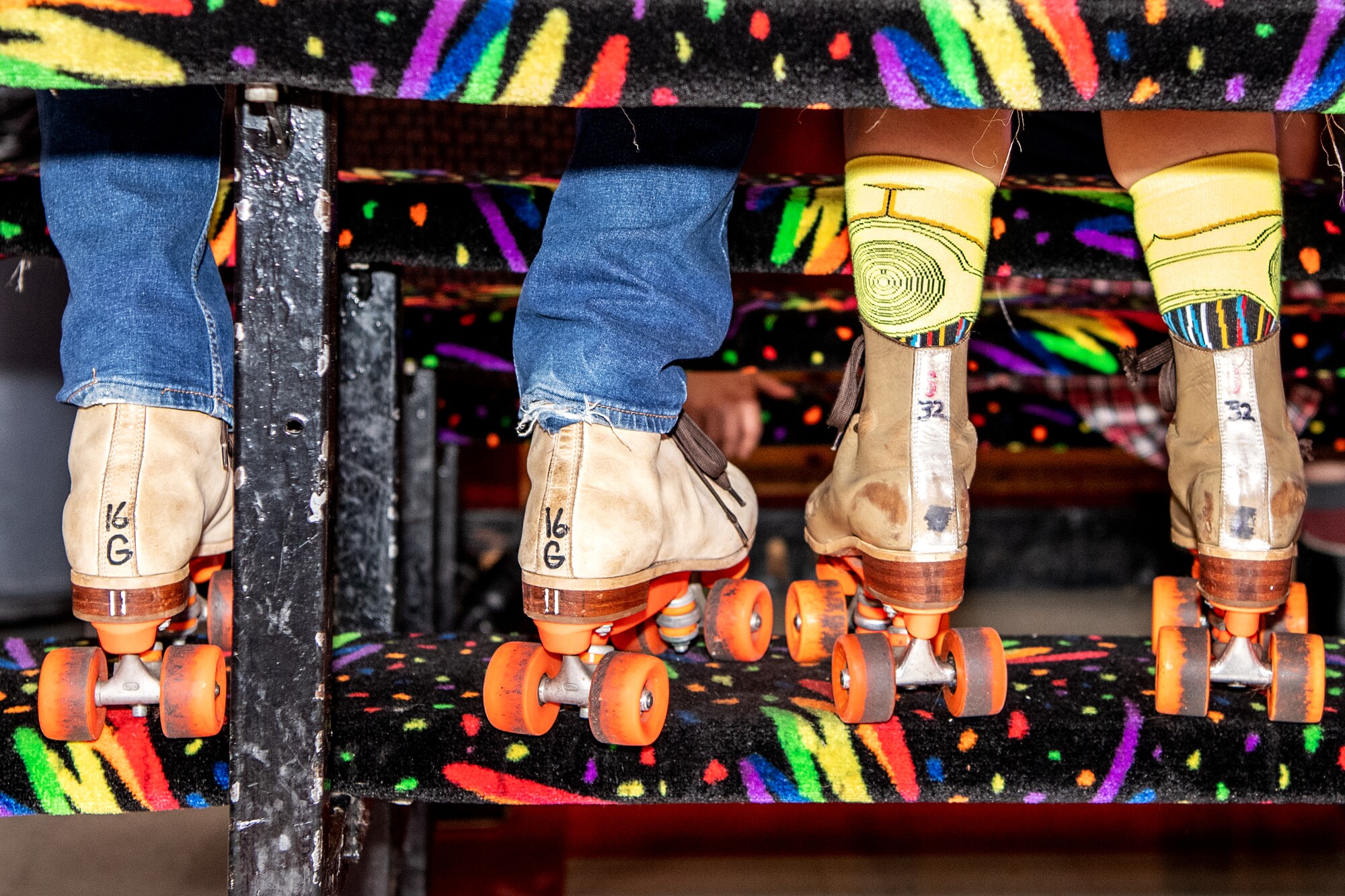 Detail shot of the back of two people's skates next to each other.