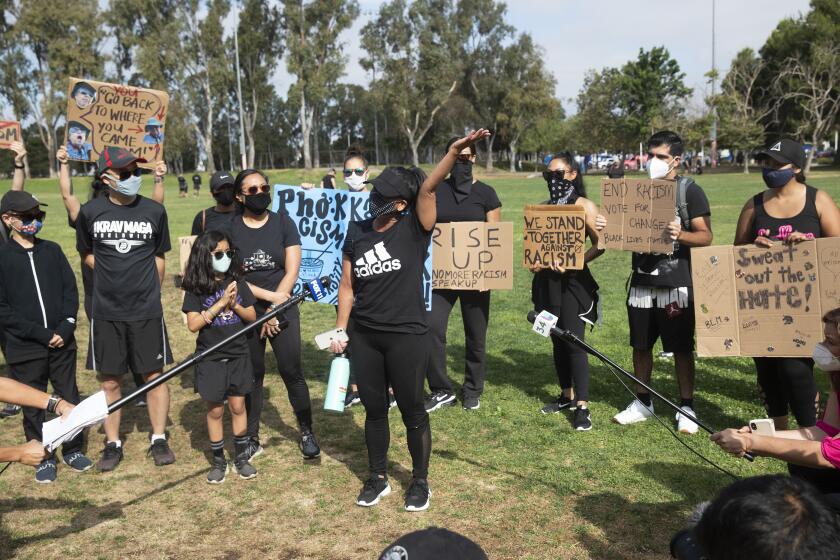 TORRANCE, CA-JUNE 12, 2020: Sherry, 38 of Torrance,(she didn't want her last name used), center, acknowledges supporters at the conclusion of a rally and workout titled, "We Sweat With You," at Charles H. Wilson Park in Torrance, where a woman made racist, anti-Asian comments to her, as she was exercising in the park, earlier this week. The same woman made anti-asian comments to an Asian male, 2nd from left, (didn't want to give his name) in the driver's seat of his car parked next to hers. In the car at the time was his 11 year old son, left, and 2 year old son, not pictured. Kayceelyn Salmimnao, 32, of Torrance, 4th from left, with her 8 year old daughter, (didn't want daughter to be named) said that she was physically attacked by the same woman at Del Amo Fashion Center in October. (Mel Melcon/Los Angeles Times).