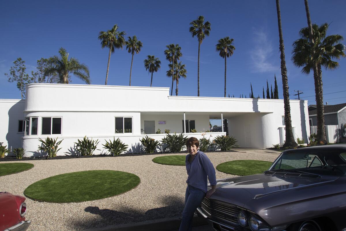 Wendy Manasse Wiese of Long Beach leans on her 1962 Cadillac parked in front of her 1930s vintage home and transformed landscape.