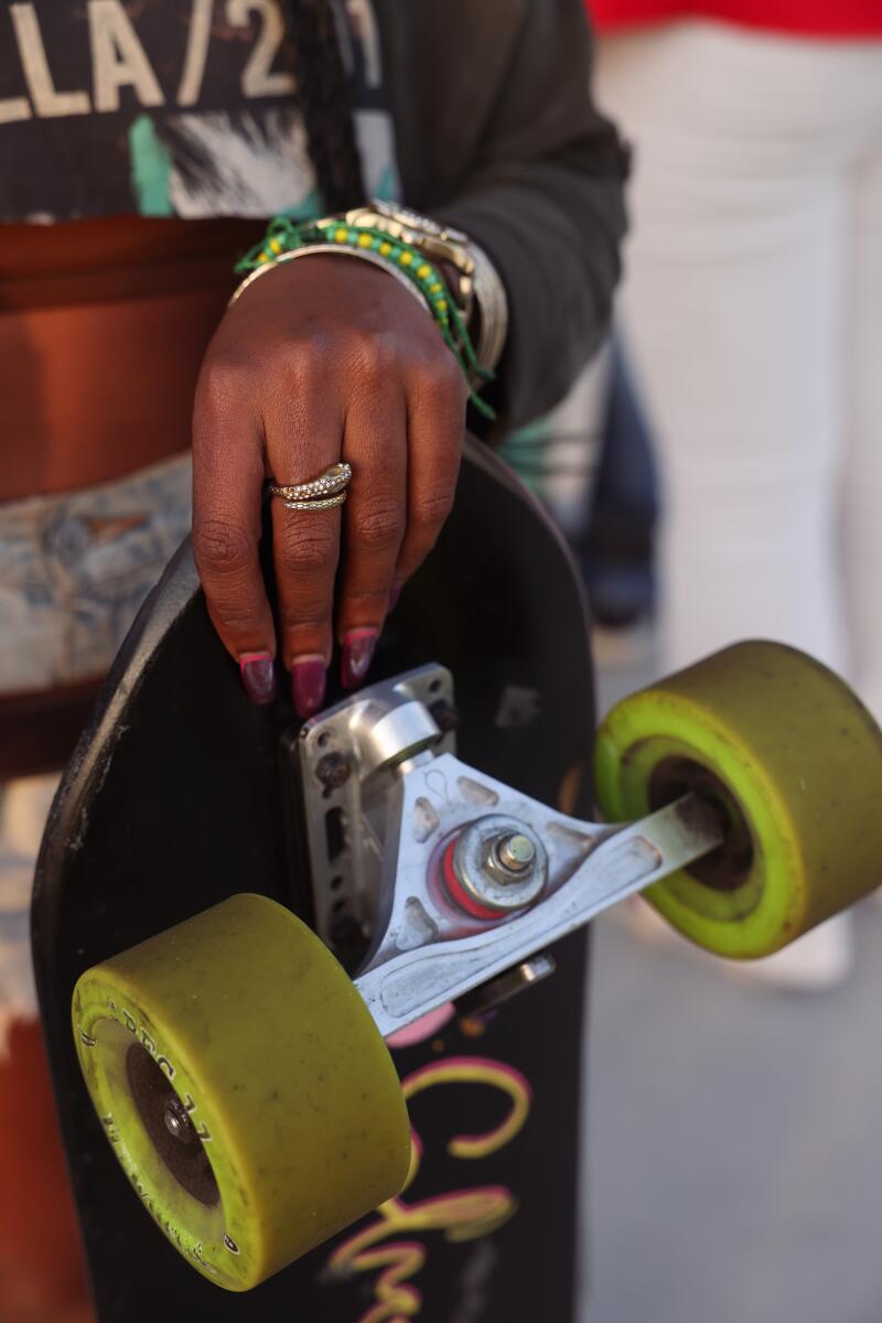 A closeup of a woman's hand holding a skateboard by one end