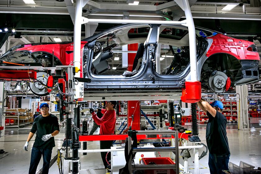 Workers assemble cars on the line at Tesla's factory in Fremont in 2015.