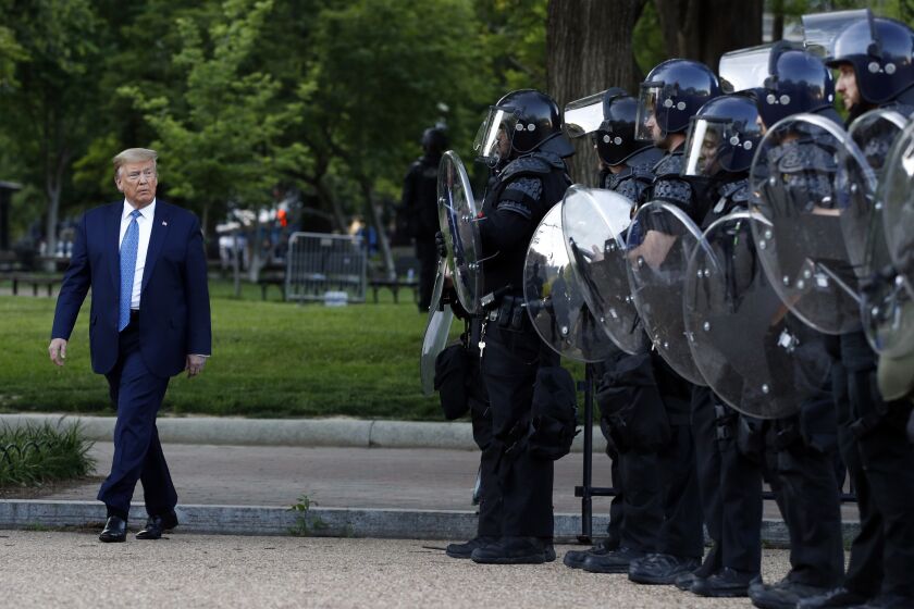 President Donald Trump walks past police in Lafayette Park after he visited outside St. John's Church across from the White House Monday, June 1, 2020, in Washington. Part of the church was set on fire during protests on Sunday night. (AP Photo/Patrick Semansky)