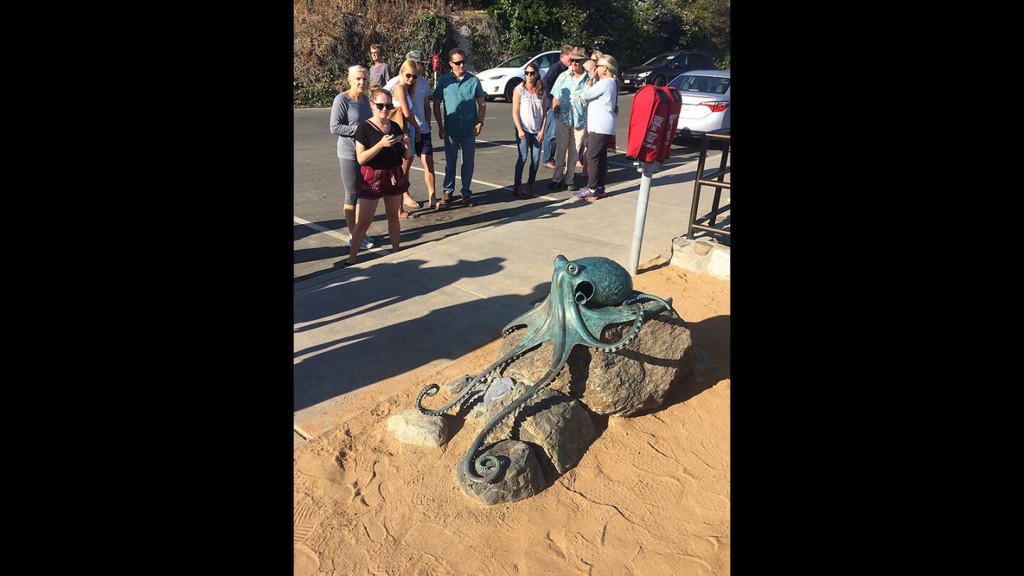 People gather to look at Casey Parlette's "Tide Pool Kraken," a bronze sculpture unveiled in a small ceremony that included family, friends, and city officials at Diver's Cove on Monday