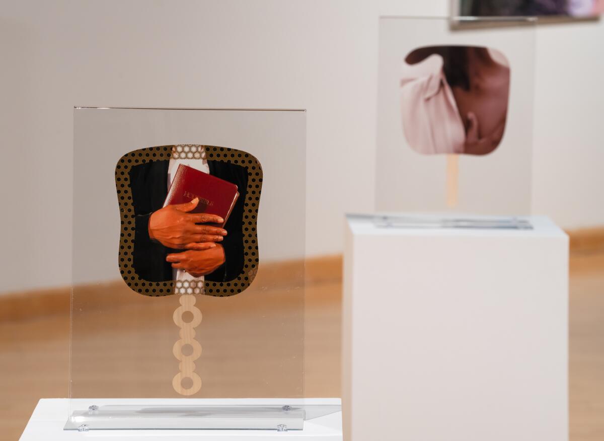 An installation view of a gallery shows paper church fans displayed in Plexiglas stands