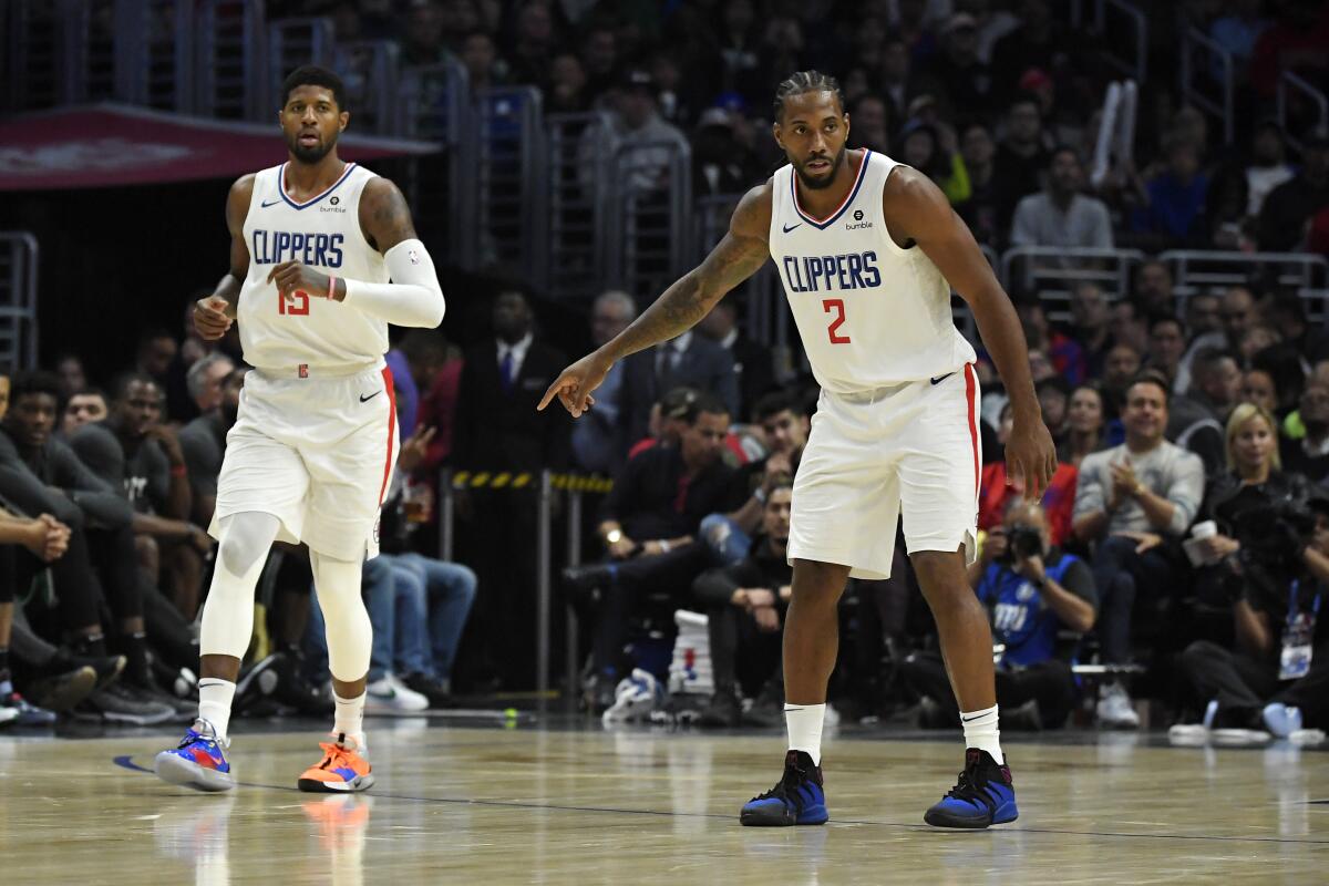 Los Angeles Clippers forward Paul George, left, and forward Kawhi Leonard stand on the court during the second half of the team's NBA basketball game against the Boston Celtics on Wednesday, Nov. 20, 2019, in Los Angeles. (AP Photo/Mark J. Terrill)