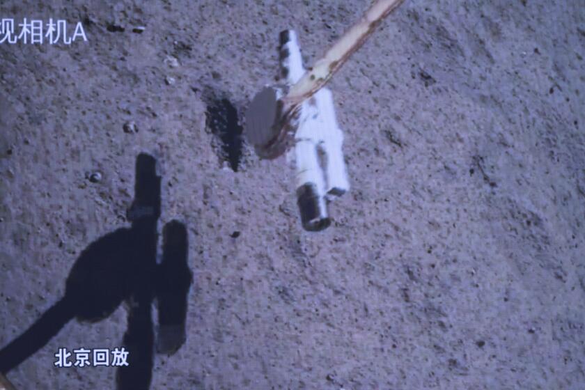 In this photo released by Xinhua News Agency, a replay screen shows Chang'e-6 probe collecting samples on the moon surface, at Beijing Aerospace Control Center (BACC) in Beijing, Tuesday, June 4, 2024. China says a spacecraft carrying rock and soil samples from the far side of the moon has lifted off from the lunar surface to start its journey back to Earth. (Jin Liwang/Xinhua via AP)