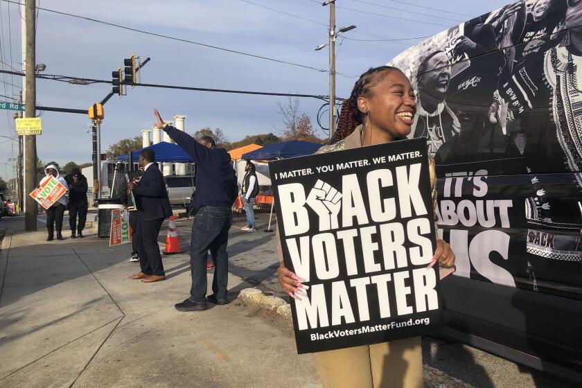 A community activist works to get out the vote near a polling station in Southwest Atlanta ahead of Georgia's Dec. 6 US Senate runoff election between Sen. Raphael Warnock and Herschel Walker.