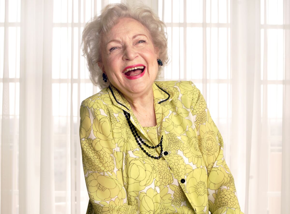 A woman wearing a patterned green jacket, laughing