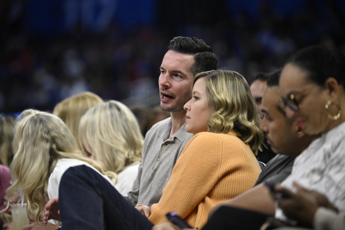 JJ Redick speaks with his wife while sitting courtside during a game between the Orlando Magic at New York Knicks.