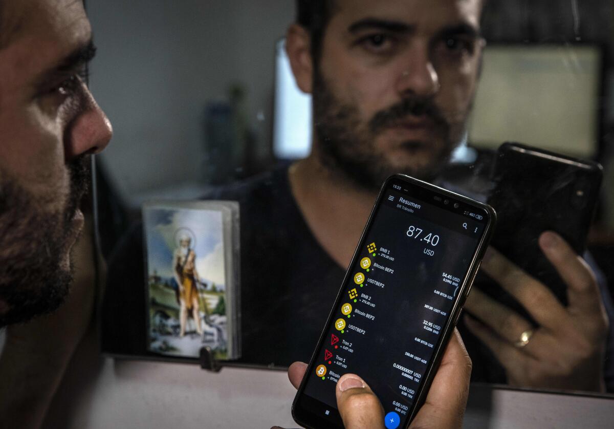 Eyonys González posa para una foto con su billetera bitcoin, en su casa de La Habana, Cuba