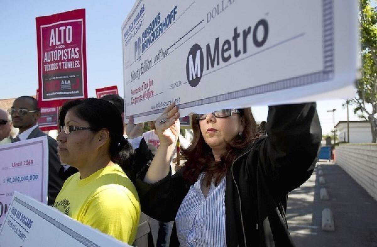 Lisa Korbatov, right, and Rosa Miranda of the Bus Riders Union hold up blank checks in an effort to highlight Measure J's corporate sponsors and beneficiaries.