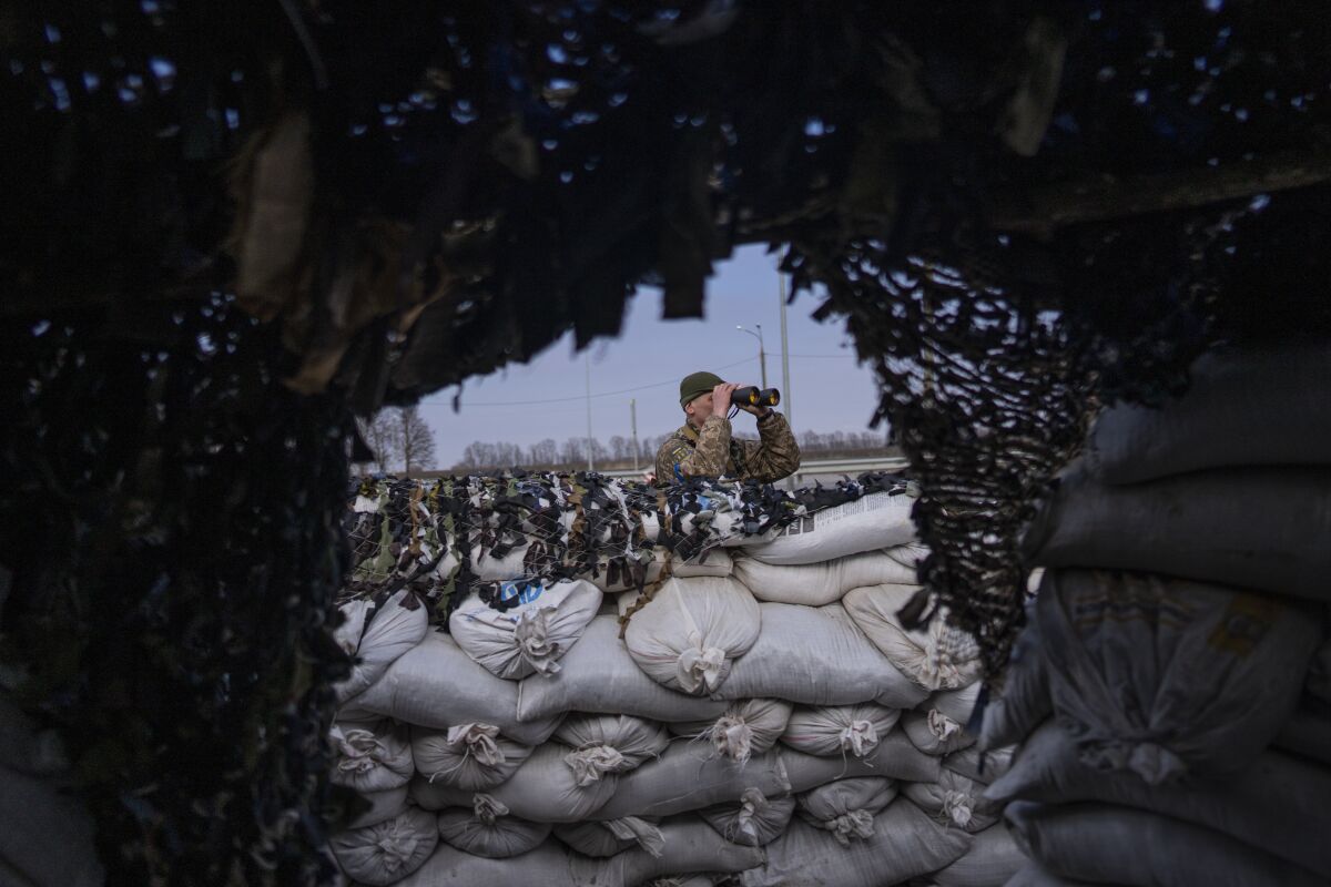A Ukrainian soldier looks through binoculars at a military check point, in Lityn, Ukraine, Wednesday, March 16, 2022. (AP Photo/Rodrigo Abd)