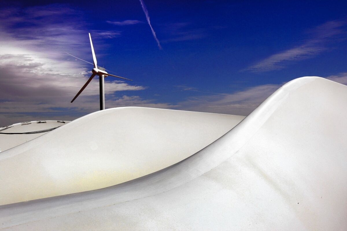 A wind turbine turns as giant turbine blades lie awaiting new construction at the National Renewable Energy Laboratory in Colorado in March 2009.