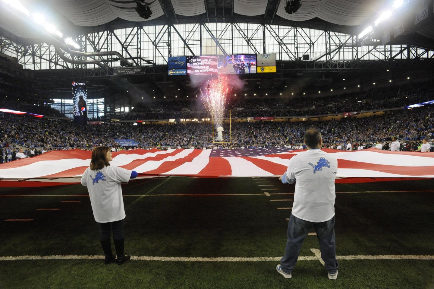 An American flag is displayed during the national anthem before the first half of an NFL football game between the Detroit Lions and the Philadelphia Eagles, Thursday, Nov. 26, 2015, in Detroit.