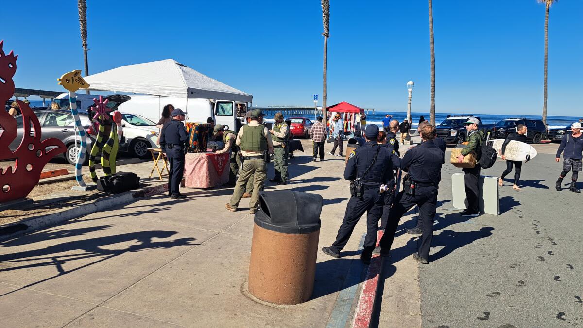 Park rangers, accompanied by San Diego police, issue a citation to a sidewalk vendor in Ocean Beach on Feb. 1.