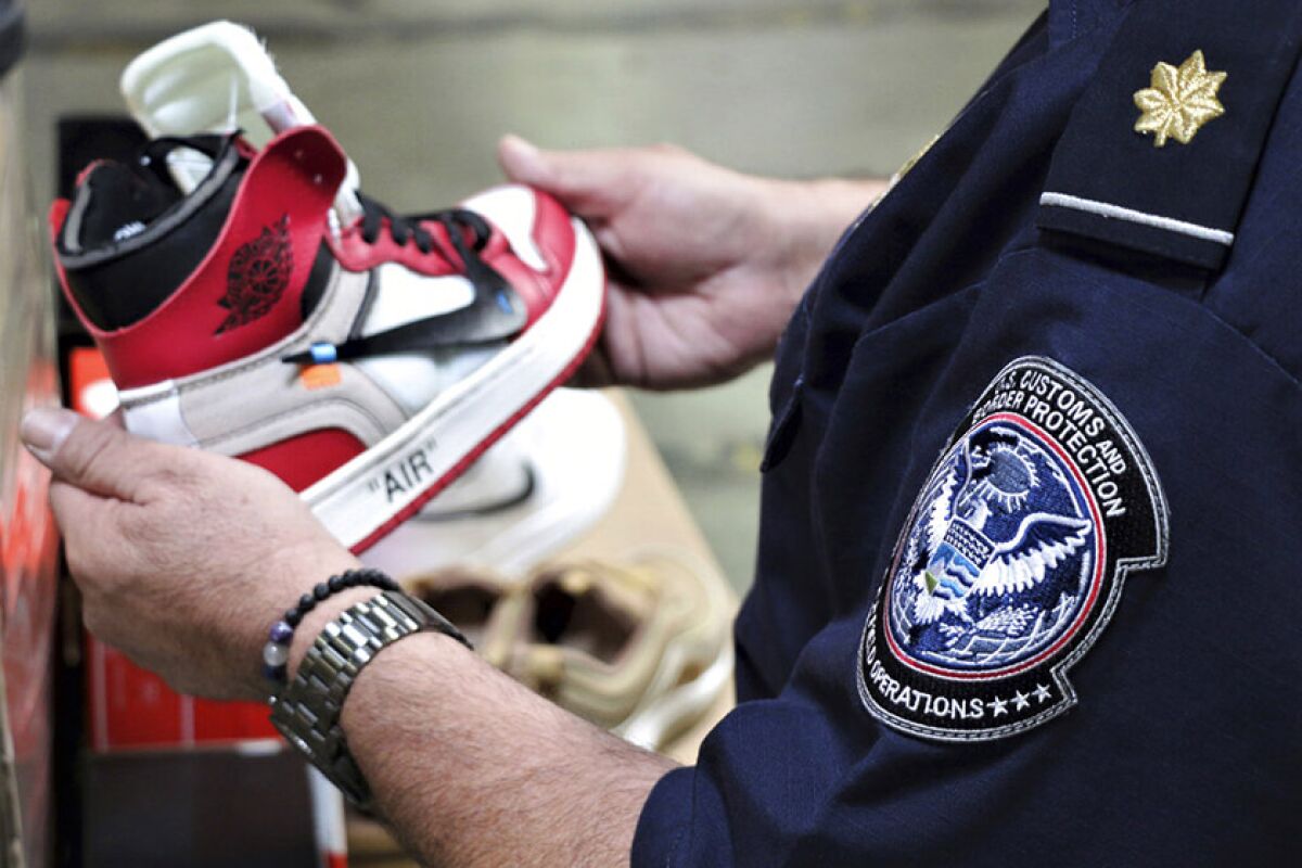 An agent from U.S. Customs and Border Protection holds one of the counterfeit Nike shoes