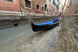 A gondola is docked on a dry canal during a low tide in Venice, Italy, Monday, Feb. 20, 2023. (AP Photo/Luigi Costantini)