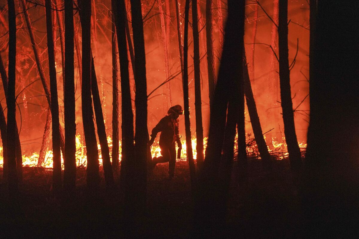 A firefighter is silhouetted against a fire burning outside the village of Roqueiro, near Oleiros, Portugal, Monday, Sept. 14, 2020. Almost 1,000 firefighters are battling a major wildfire in central Portugal. Officials said that strong winds were pushing the flames through dense and hilly woodland, much of it hard to reach. (AP Photo/Sergio Azenha)